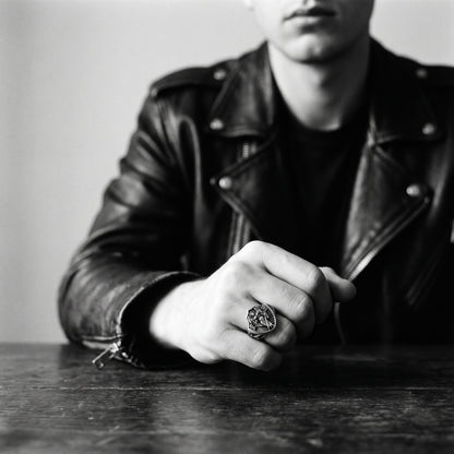 Black and white photo of a fist resting on a wooden table wearing the Archangel Michael signet ring