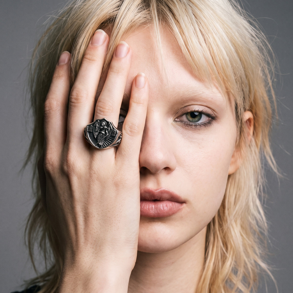 Blonde model with her hand over half her face wearing the Archangel Michael signet ring