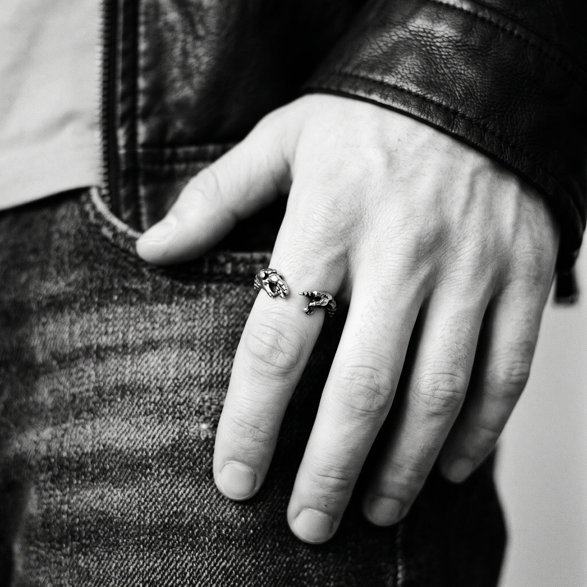 Young man's hand in a black leather jacket wearing the Ascension hands of God ring, black and white 35mm film