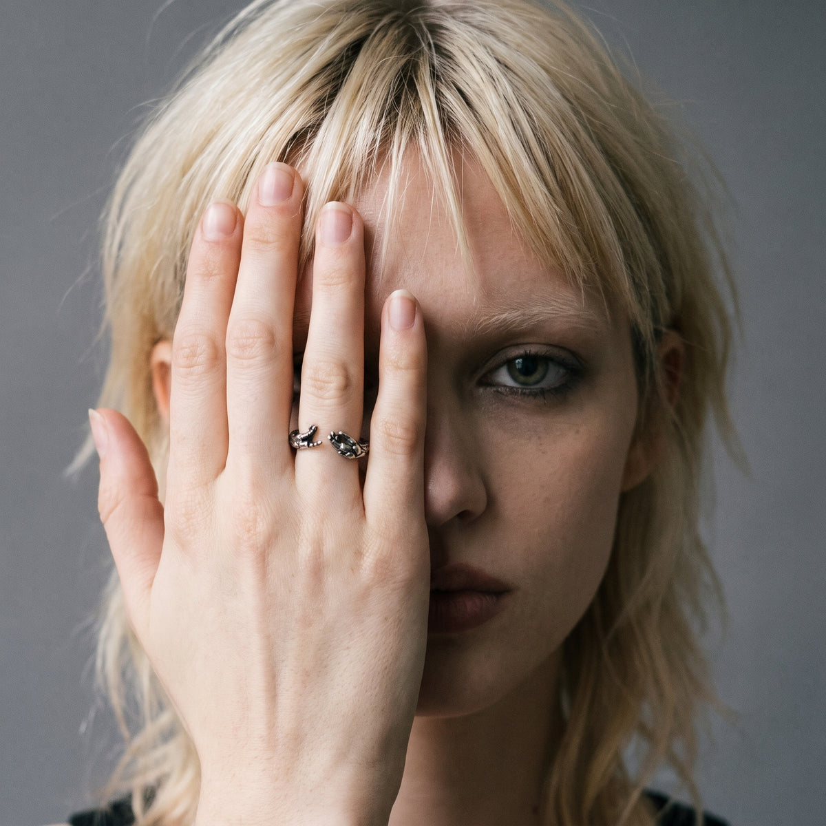 Blonde model with her hand over her face wearing the Ascension hands of God ring, vintage film photo