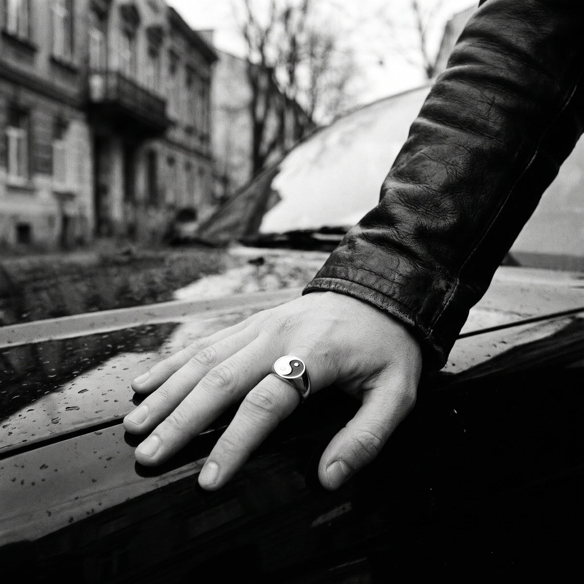 Black and white photo of a hand resting on a car hood wearing the Eclipse yin-yang signet ring
