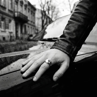 Black and white photo of a hand resting on a car hood wearing the Eclipse yin-yang signet ring