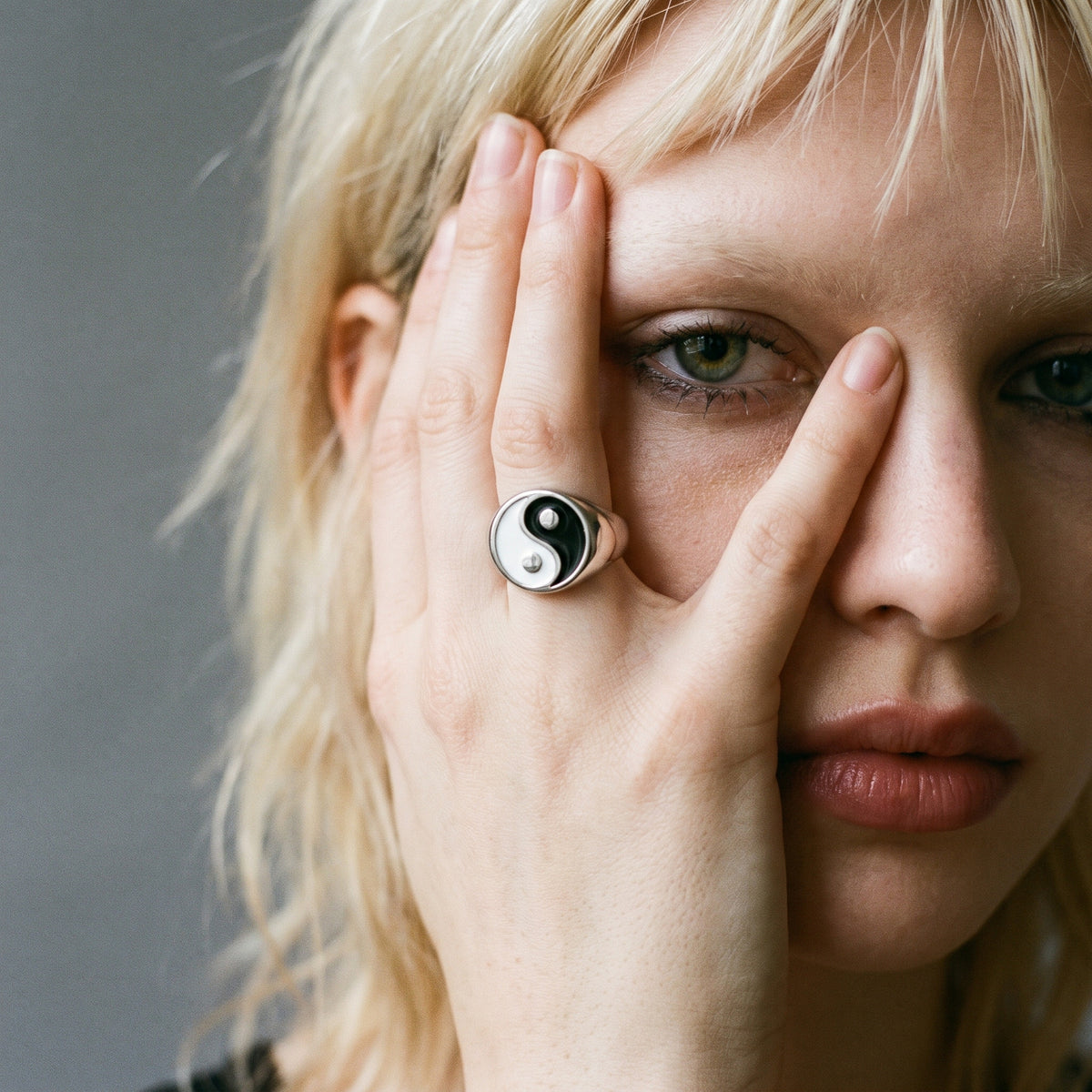 Blonde model with her hand over half her face wearing the Eclipse yin-yang signet ring