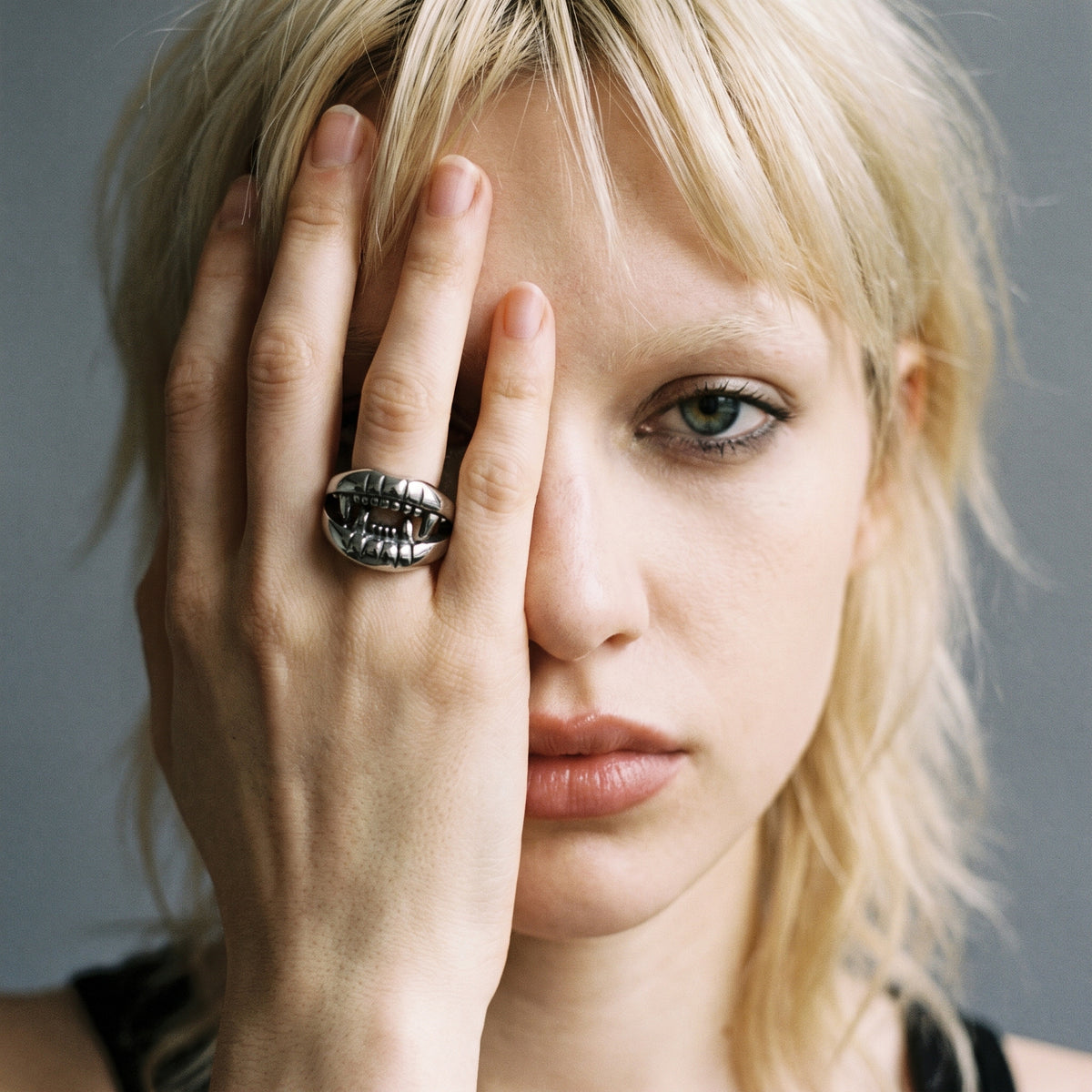 Blonde model with her hand over her face wearing the Fang devil mouth ring, vintage film photo