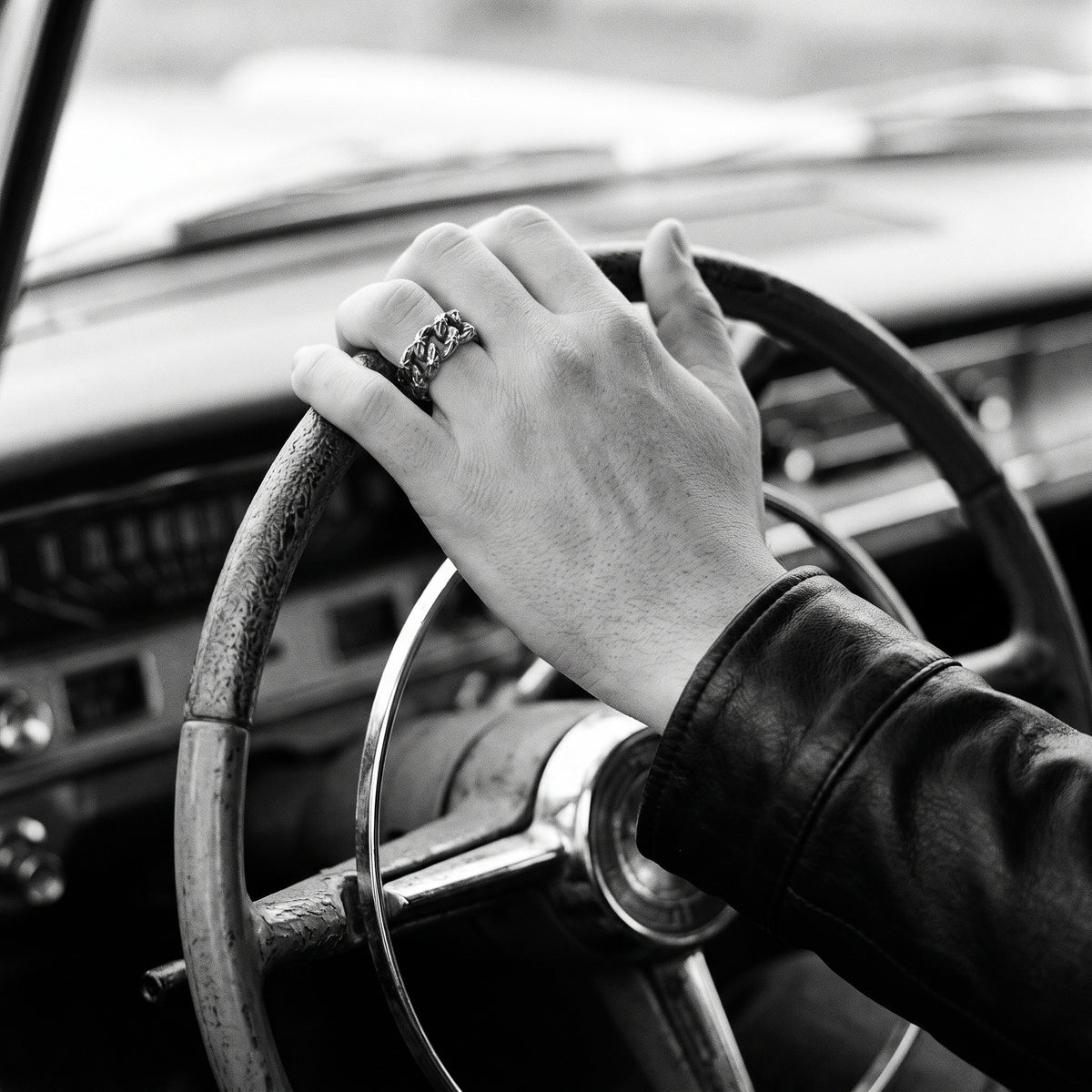 Black and white photo of a hand on a vintage car steering wheel wearing the Havana Cuban link ring
