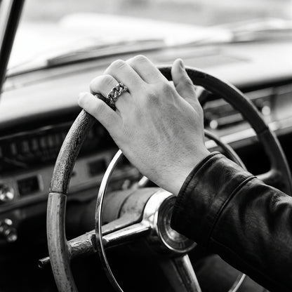 Black and white photo of a hand on a vintage car steering wheel wearing the Havana Cuban link ring