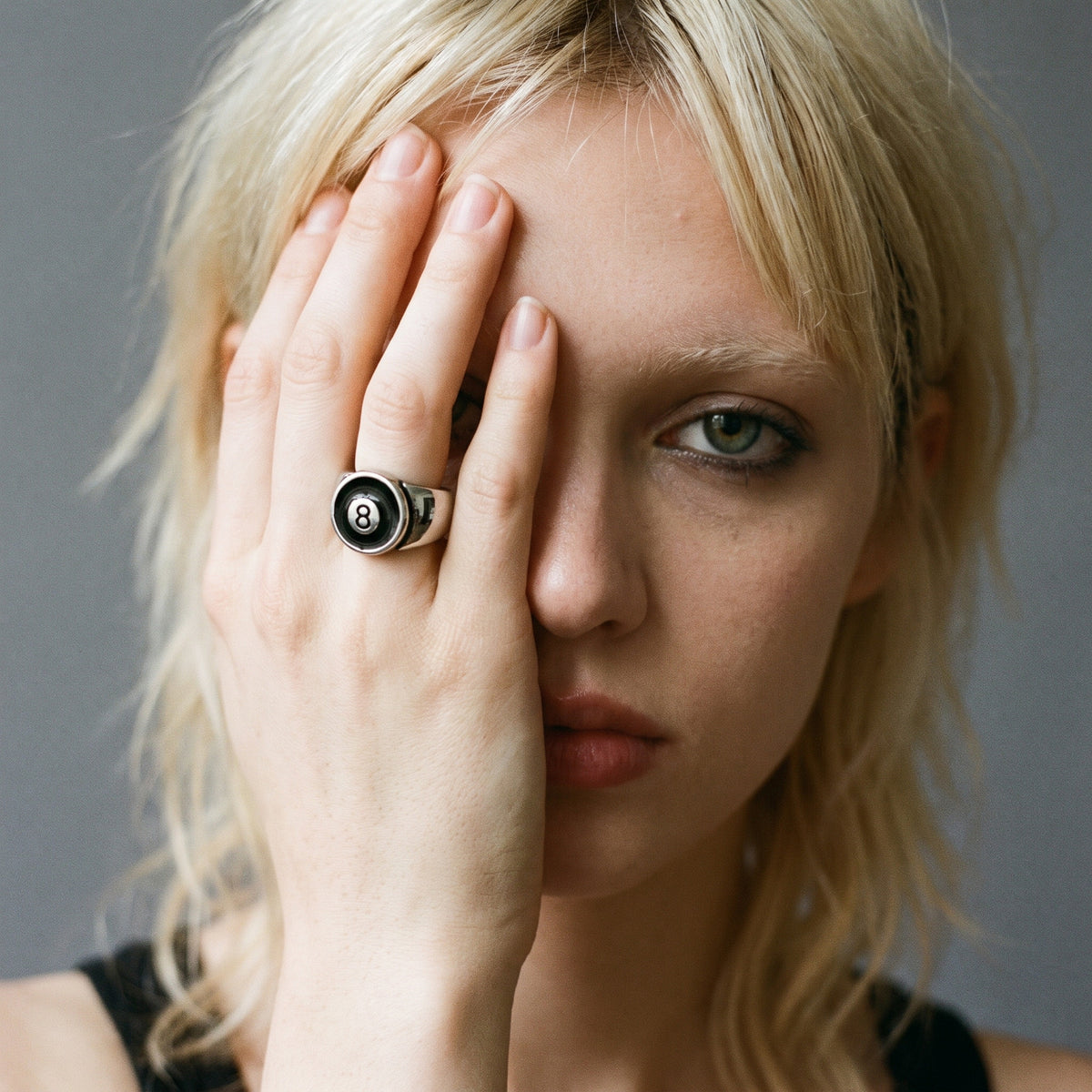 Blonde model with her hand over her face wearing the Hustler 8-ball ring, vintage film photo