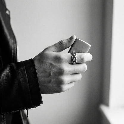 Black and white photo of a hand holding a closed lighter wearing the Inferno flame ring