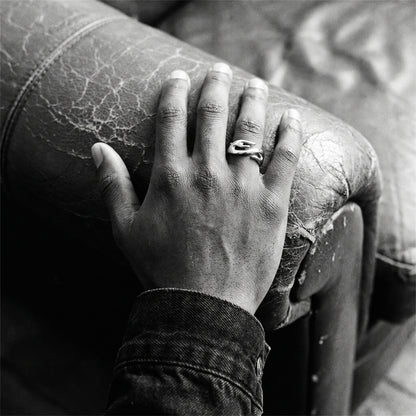 Black and white photo of a hand resting on a leather couch armrest wearing the Inferno flame ring