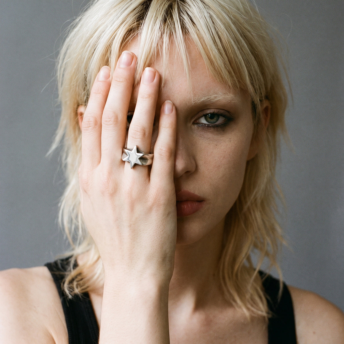 Blonde model with her hand over her face wearing the Polaris six-point star ring, vintage film photo