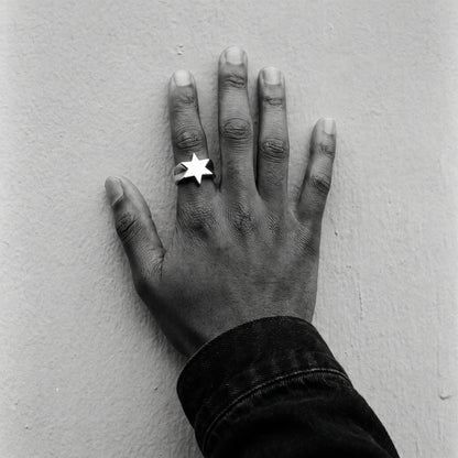 Man's hand on a wall wearing the Polaris six-point star ring, black and white film photo