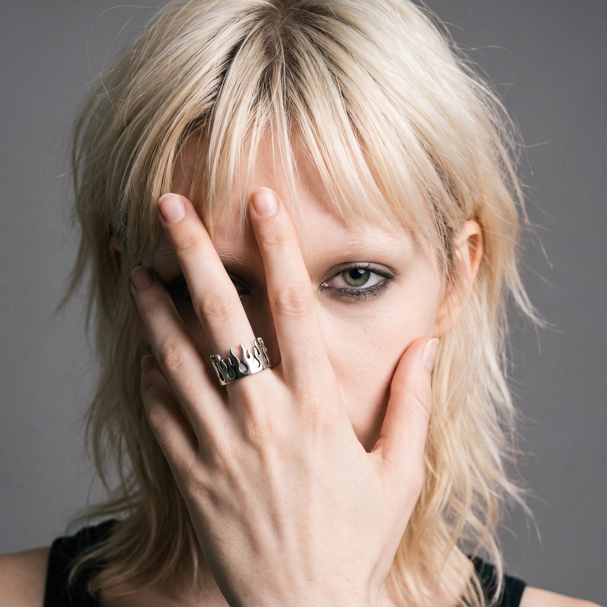 Blonde model with her hand over her face wearing the Pyre Flame Open Band Ring