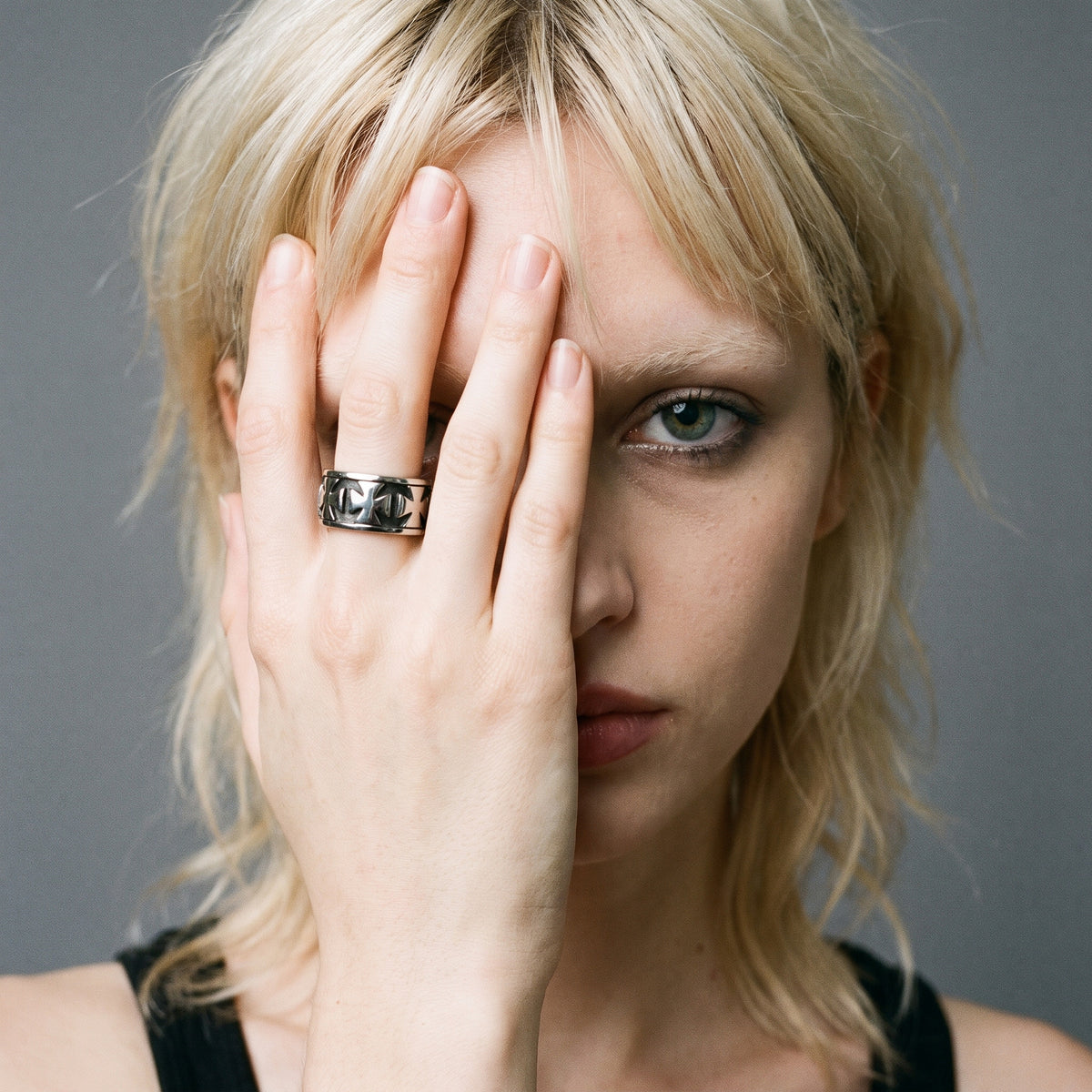 Blonde model with her hand over her face wearing the Sacrament cross band ring, vintage film photo
