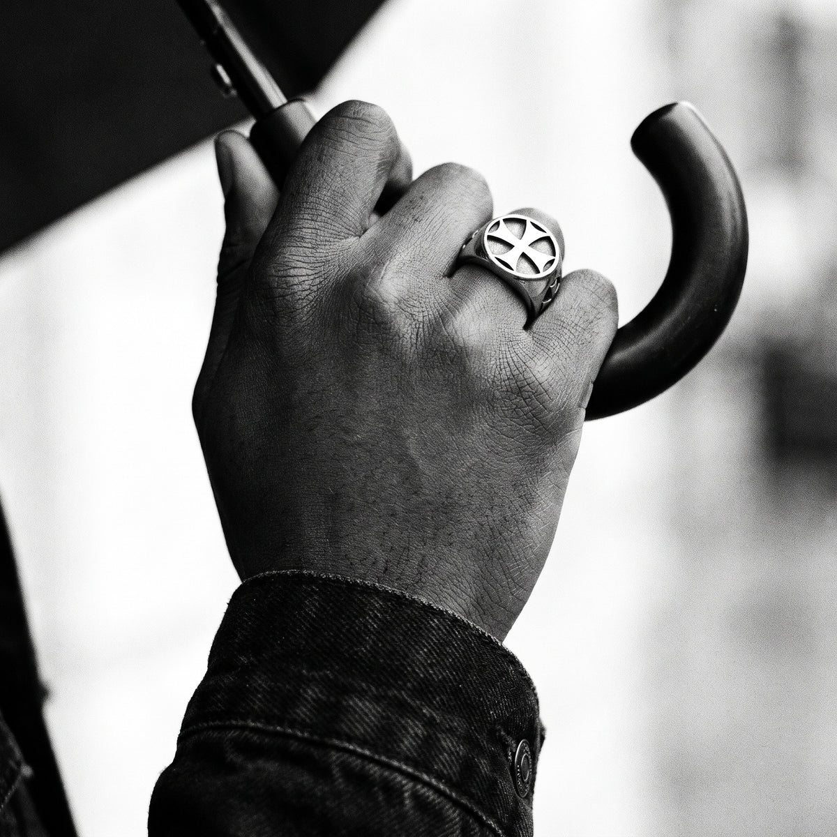 Black and white photo of a hand gripping a black umbrella handle wearing the Seneschal Templar cross signet ring