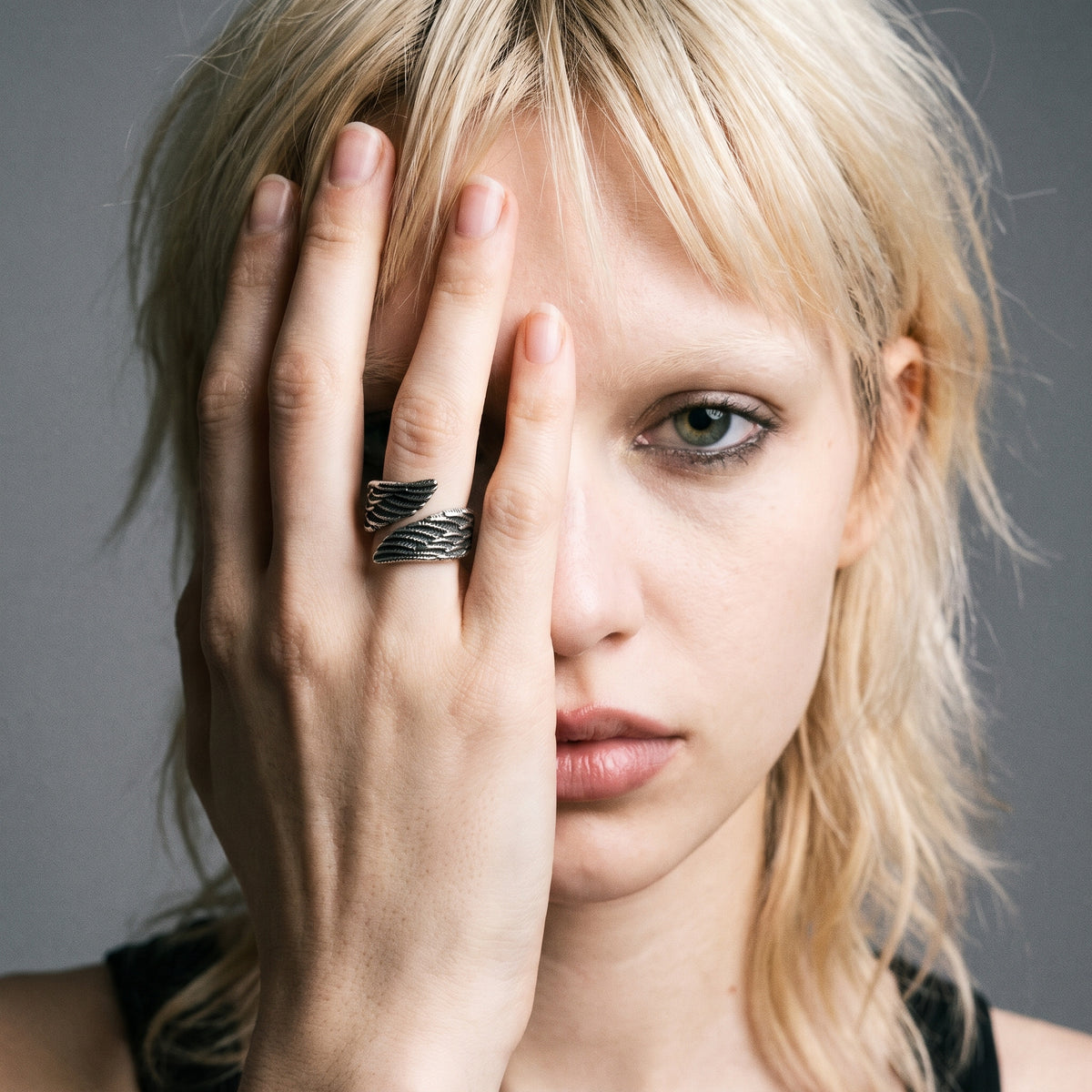 Blonde model with her hand over her face wearing the Seraph winged open ring, vintage film photo