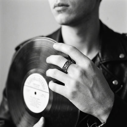 Black and white photo of a hand holding a vinyl record wearing the Skald Viking scrollwork ring