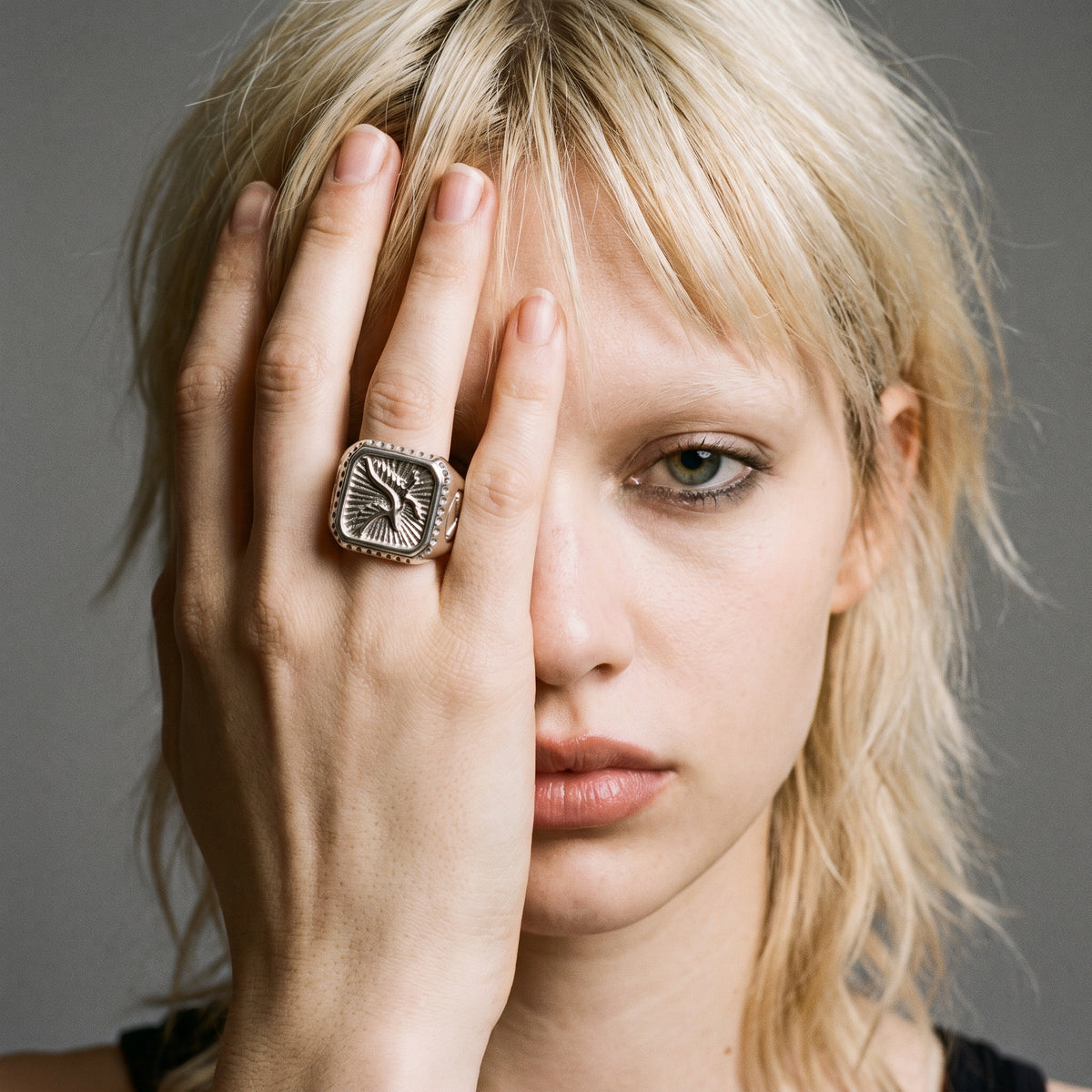 Blonde model with her hand over half her face wearing the Talon winged eagle signet ring