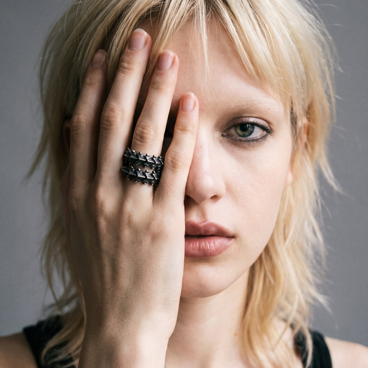 Blonde model with her hand over half her face wearing the Vertebra dragon bone ring