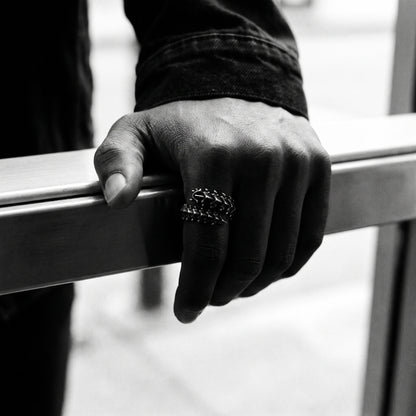 Black and white photo of a hand gripping a metal door push bar wearing the Vertebra dragon bone ring
