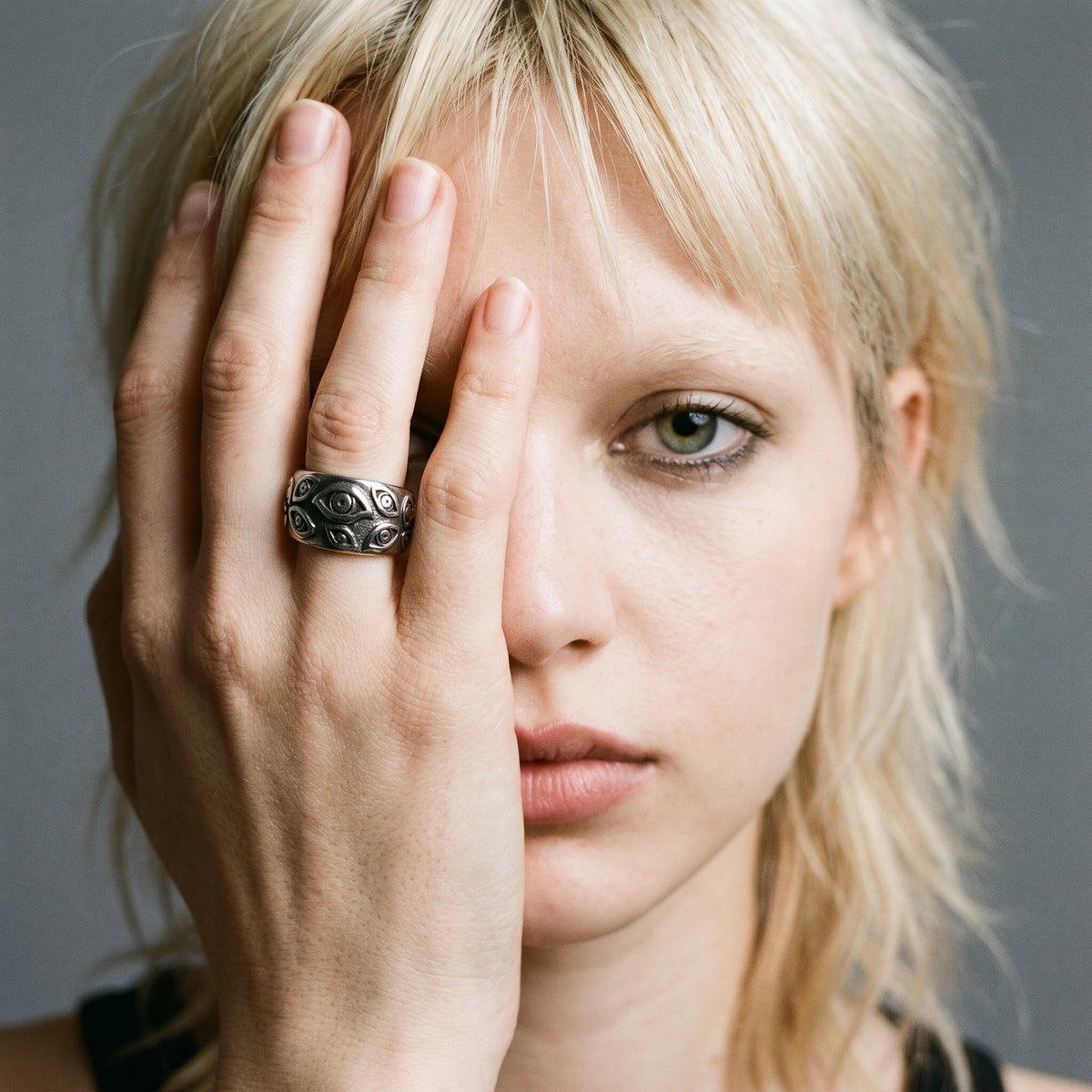 Blonde model with her hand over her face wearing the Watcher eye ring, vintage film photo