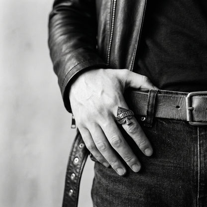 Young man's hand in a black leather jacket, thumb in belt, wearing the Wildcard ace of spades ring, black and white 35mm film